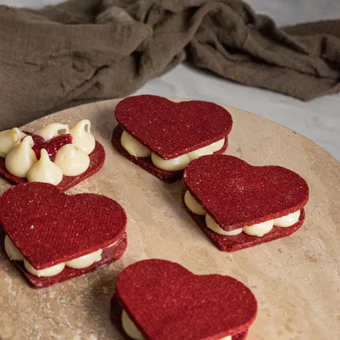 Heart-shaped red velvet vegan alfajores with vanilla cream